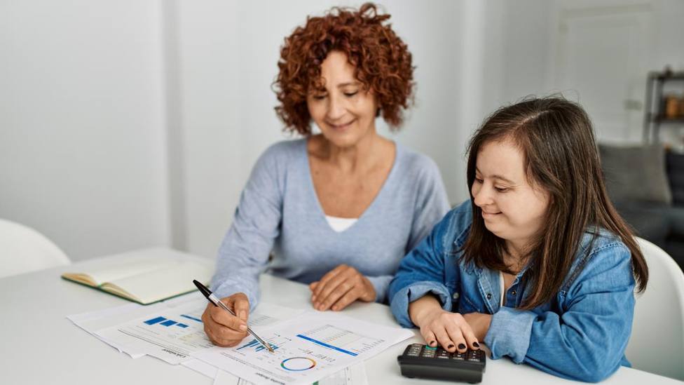 Una tutora amb una persona amb discapacitat, ensenyant-li com llegir i interpretar les factures.