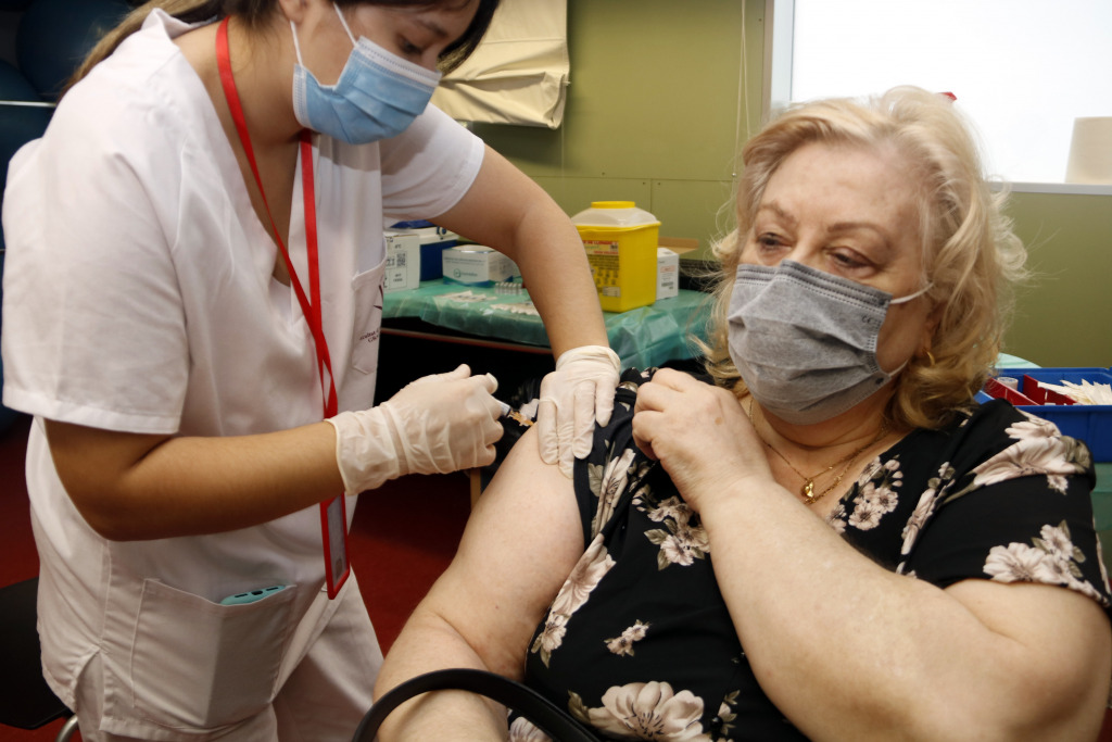 Una dona gran està sent vacunada per una infermera de grip i Covid-19.