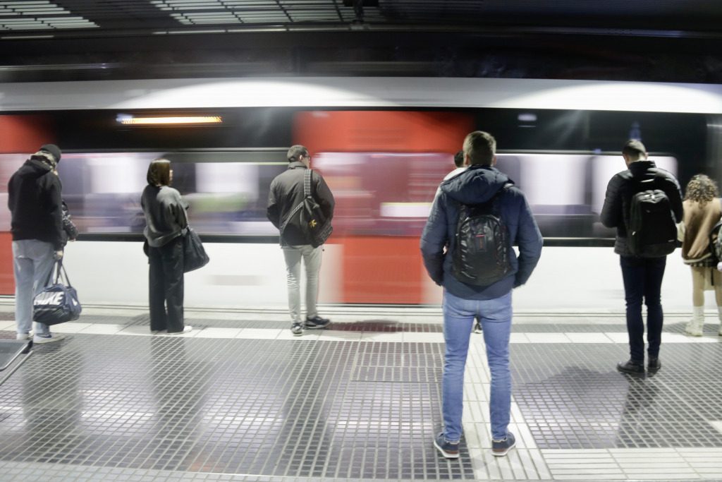 Andana al metro de Barcelona, amb passatgers d'esquenes i el convoi passant