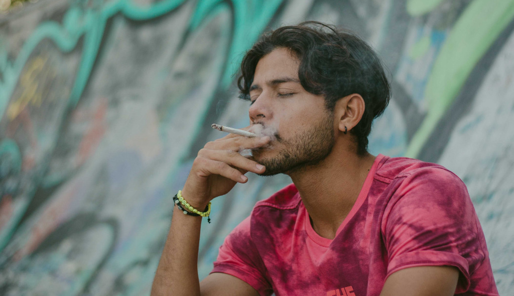 Un jove fumant en un parc de monopatins