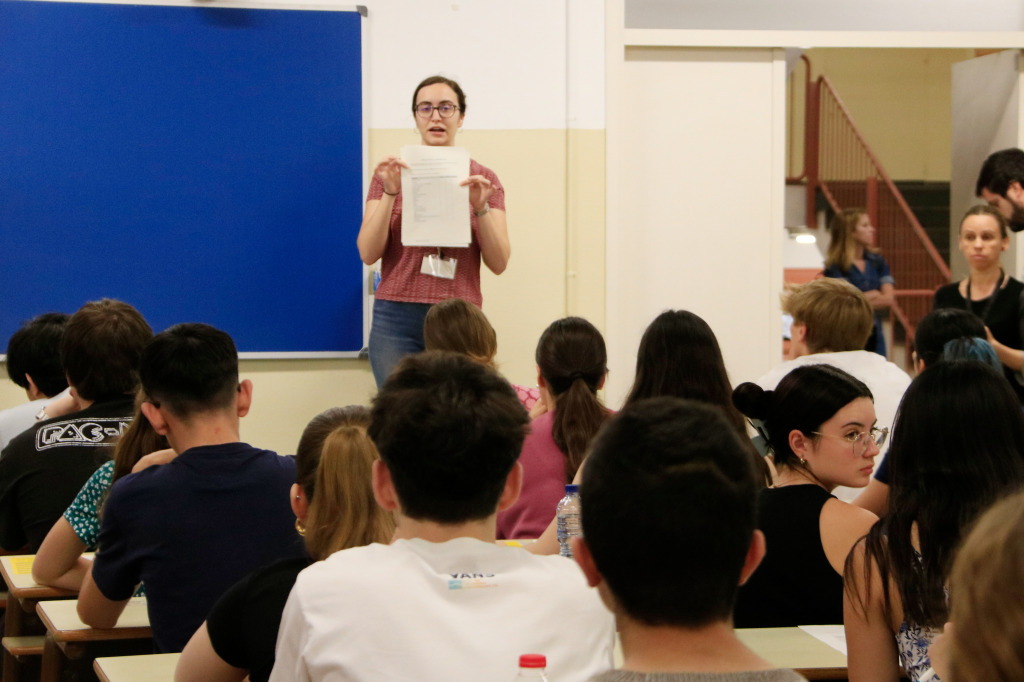 Alumnes d'esquena i una professora d'universitat mostrant uns documents